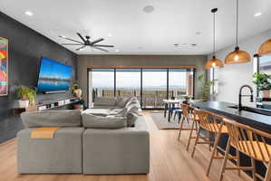 Open-concept living space featuring wood-finish flooring, a contemporary ceiling fan, and a built-in media console