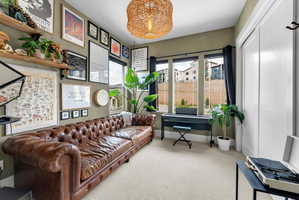 Carpeted interior space featuring a wall of framed art and shelving