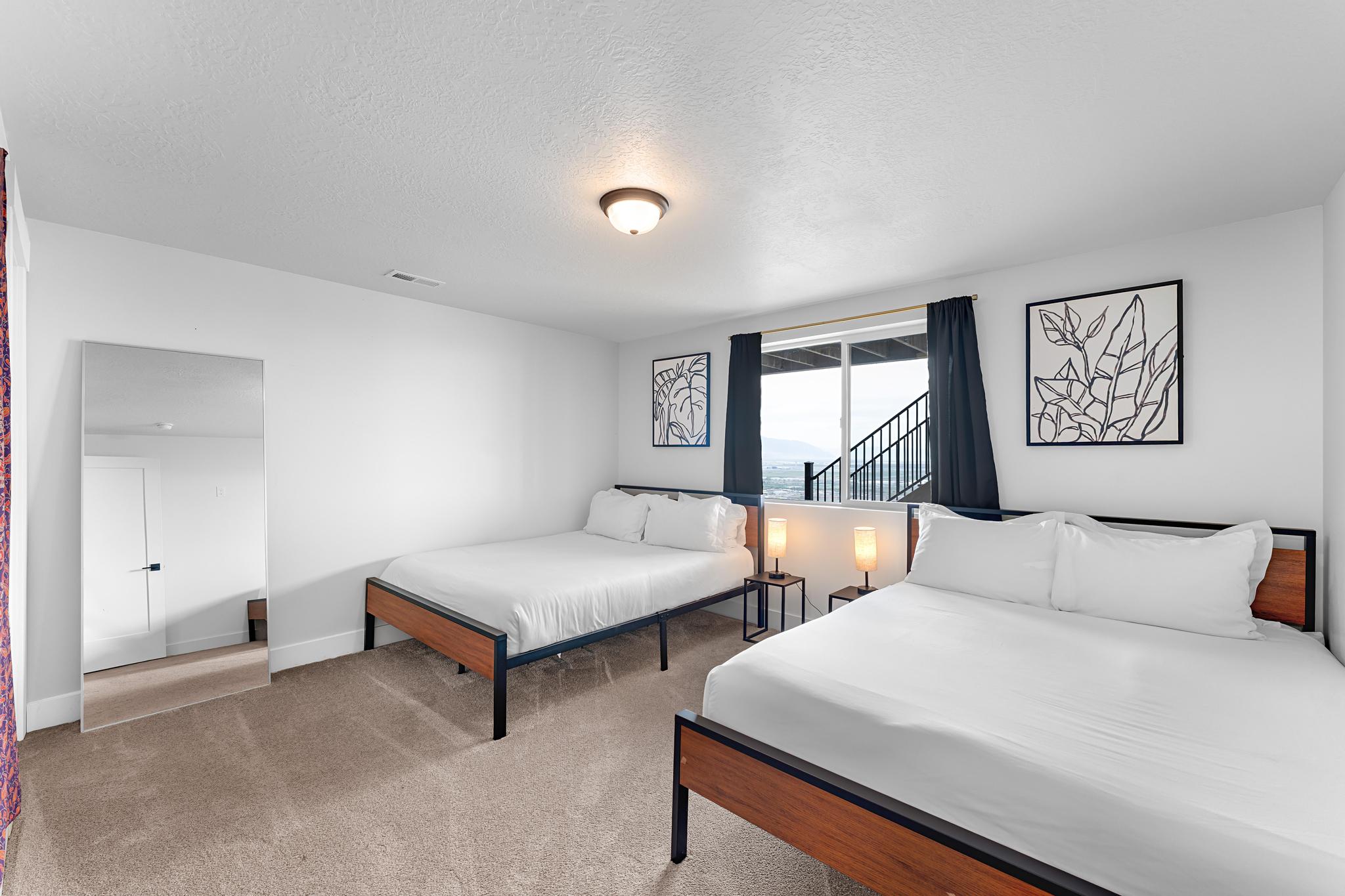 Carpeted room with white walls, featuring a sliding glass door with dark curtains, a contemporary ceiling light fixture, and a full-length mirror
