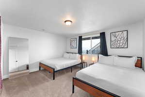 Carpeted room with white walls, featuring a sliding glass door with dark curtains, a contemporary ceiling light fixture, and a full-length mirror