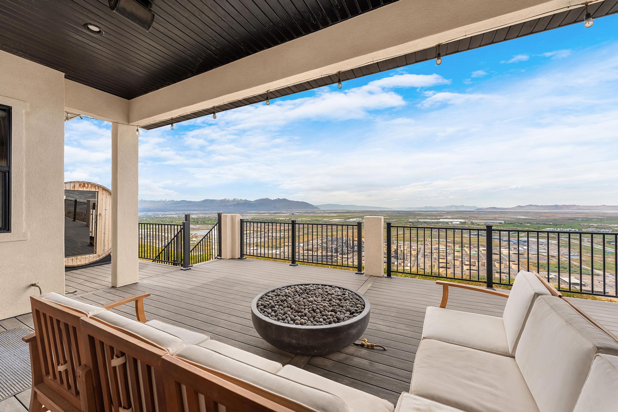 Expansive outdoor deck featuring composite decking, a built-in fire pit, and durable black metal railings