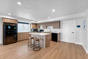 Contemporary kitchen featuring light wood-finish cabinetry, a central island with a light-toned countertop, and stainless steel appliances