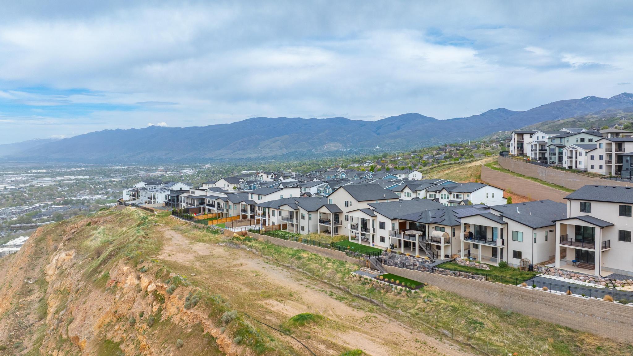 Hillside community featuring modern residences with multiple balconies and dark-pitched roofs