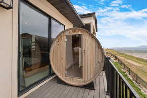Barrel sauna on a composite deck, featuring a sliding glass door and black metal railing