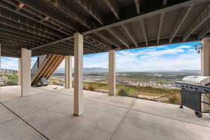 Expansive covered concrete patio with open-air design, supported by substantial pillars