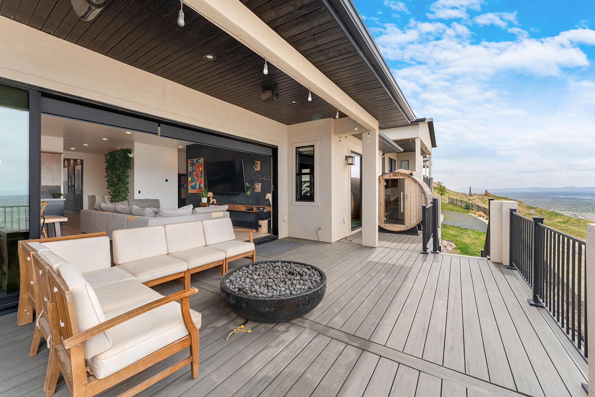 Expansive outdoor deck featuring composite decking, a built-in fire pit, and black metal railings