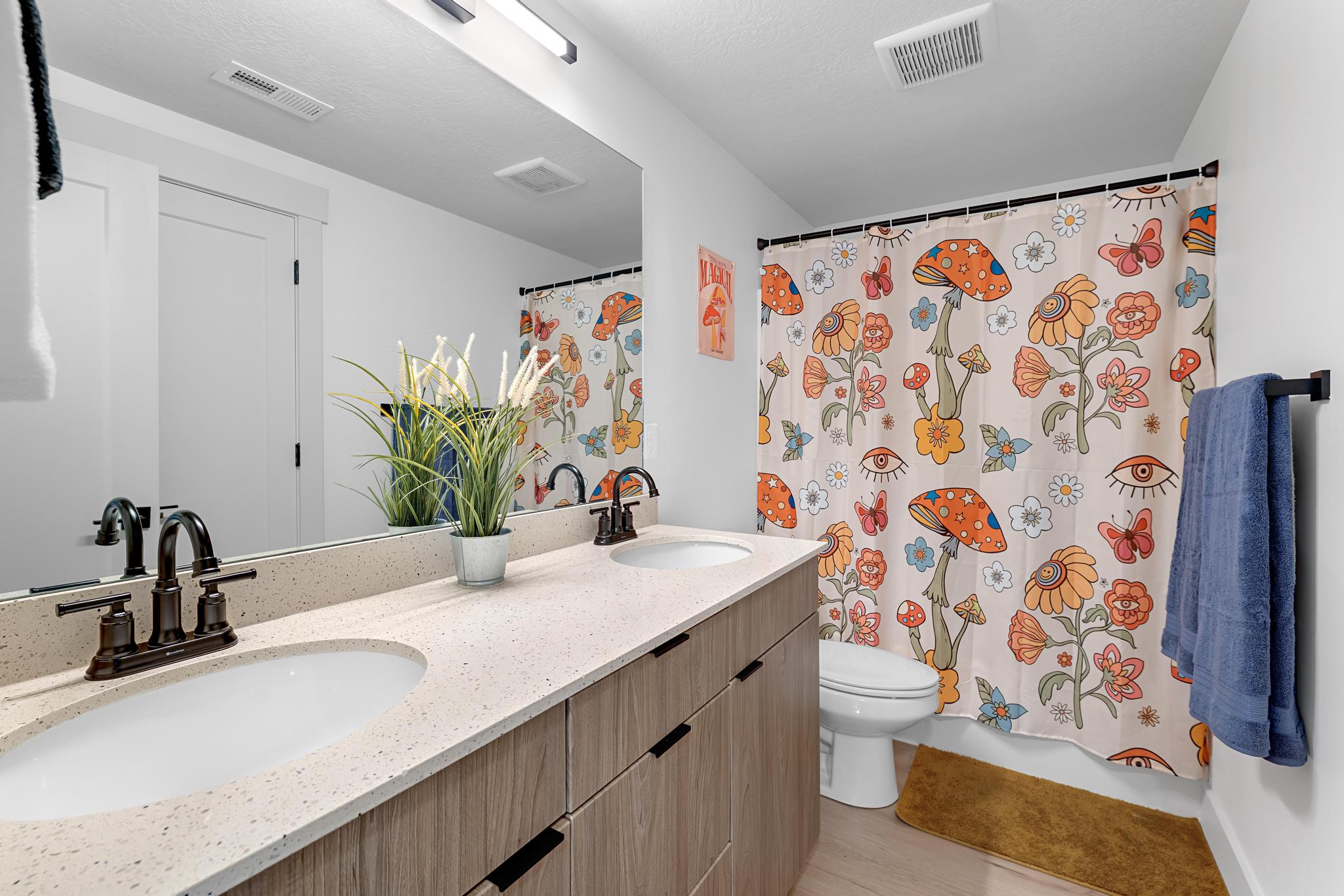 Dual vanity featuring light-toned countertops with integrated sinks and dark bronze-finish fixtures