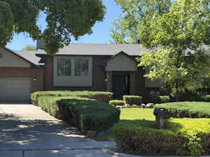 Brick exterior residence featuring a dark paneled entry door, a two-car garage, and a bay window with a light-toned panel accent
