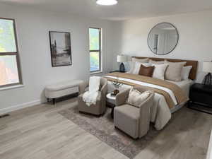 Spacious room featuring light wood-finish flooring, two windows with white trim, and recessed lighting