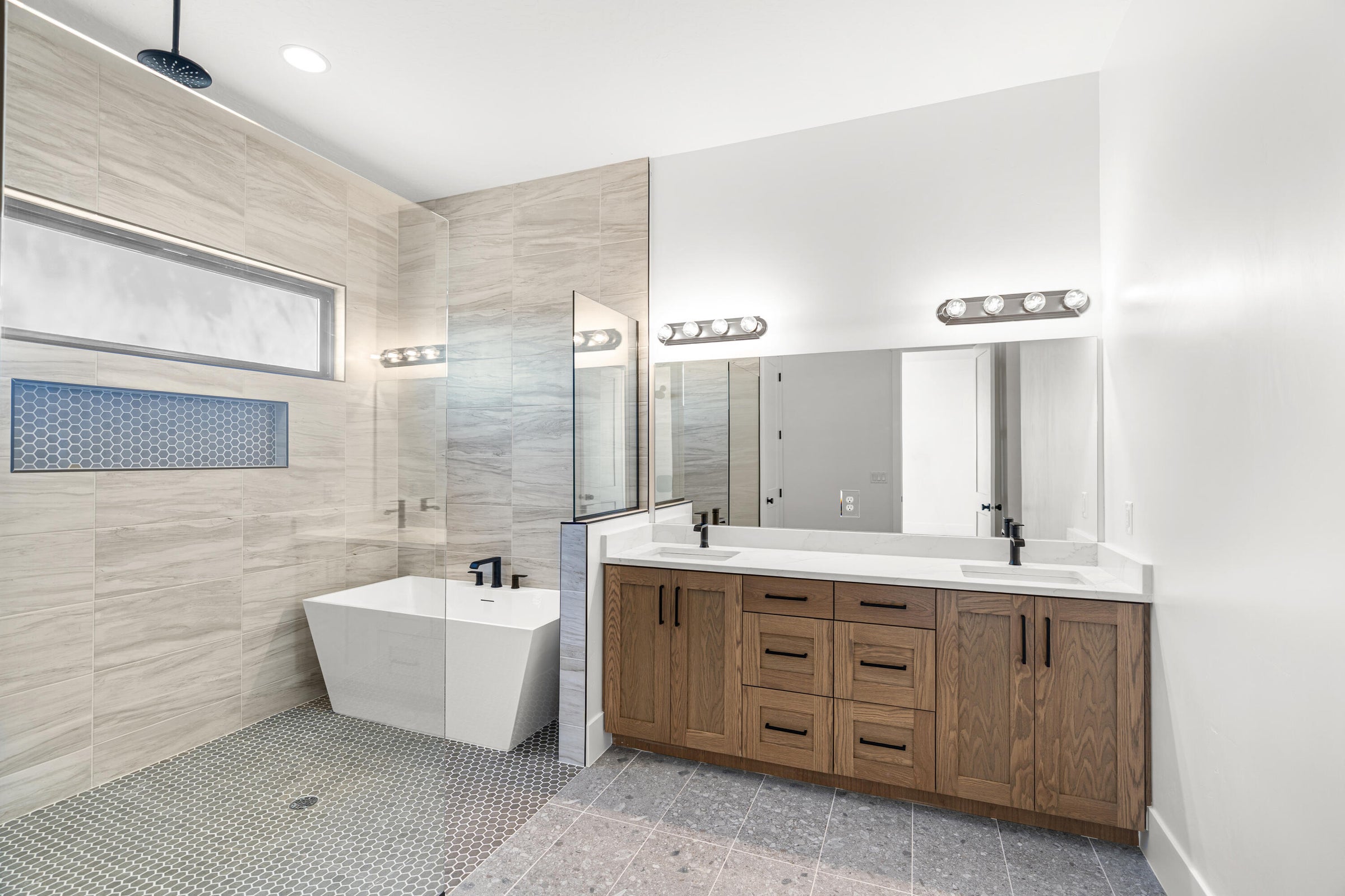 Contemporary bathroom featuring a freestanding soaking tub, a dual vanity with wood-finish cabinetry, and a spacious walk-in shower with rain head fixture