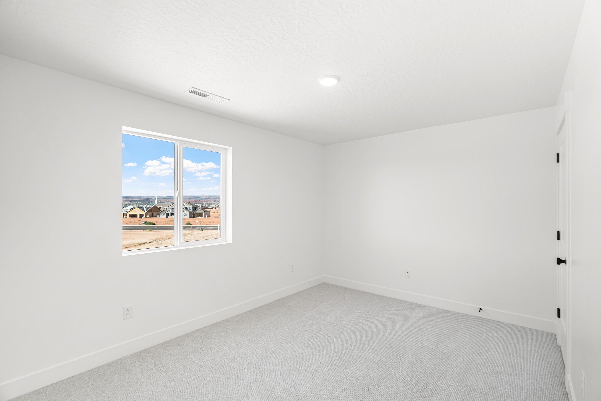 Bright interior space featuring a double-pane window, light-colored carpeting, white walls, and a recessed ceiling light