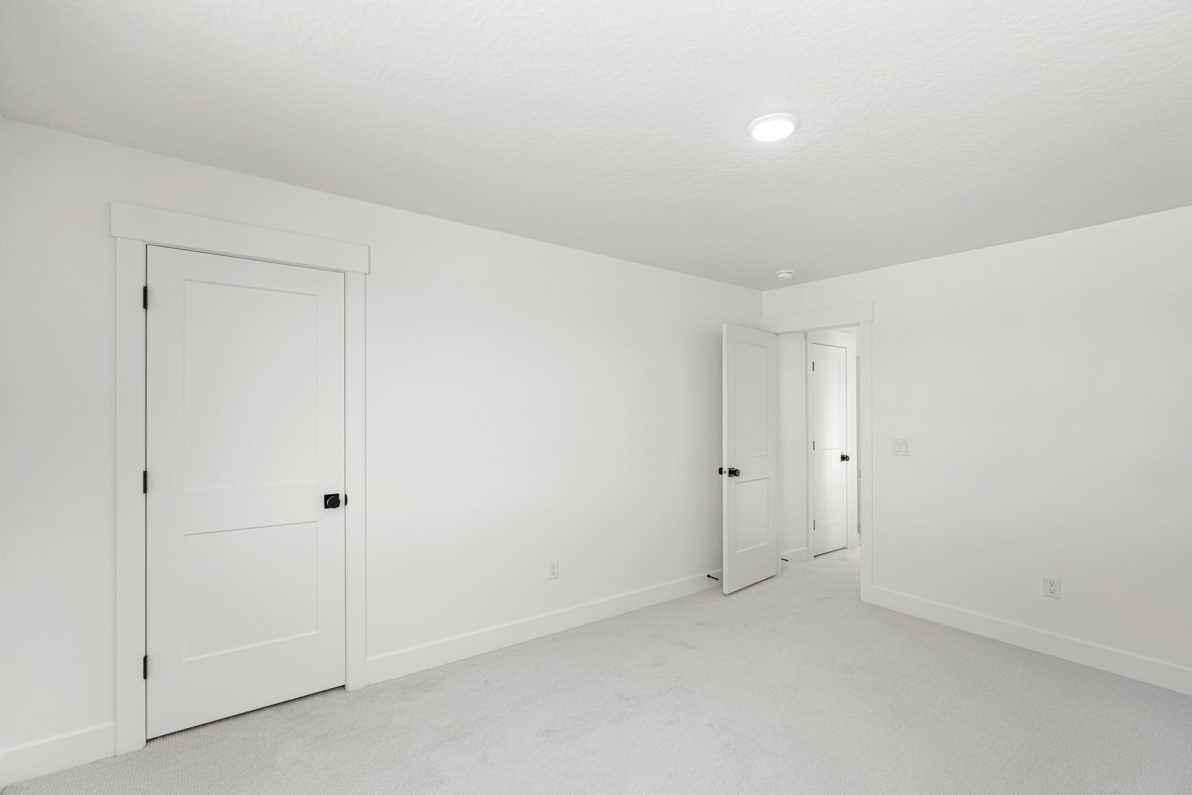 White interior door with black hardware, complementing a neutral color palette