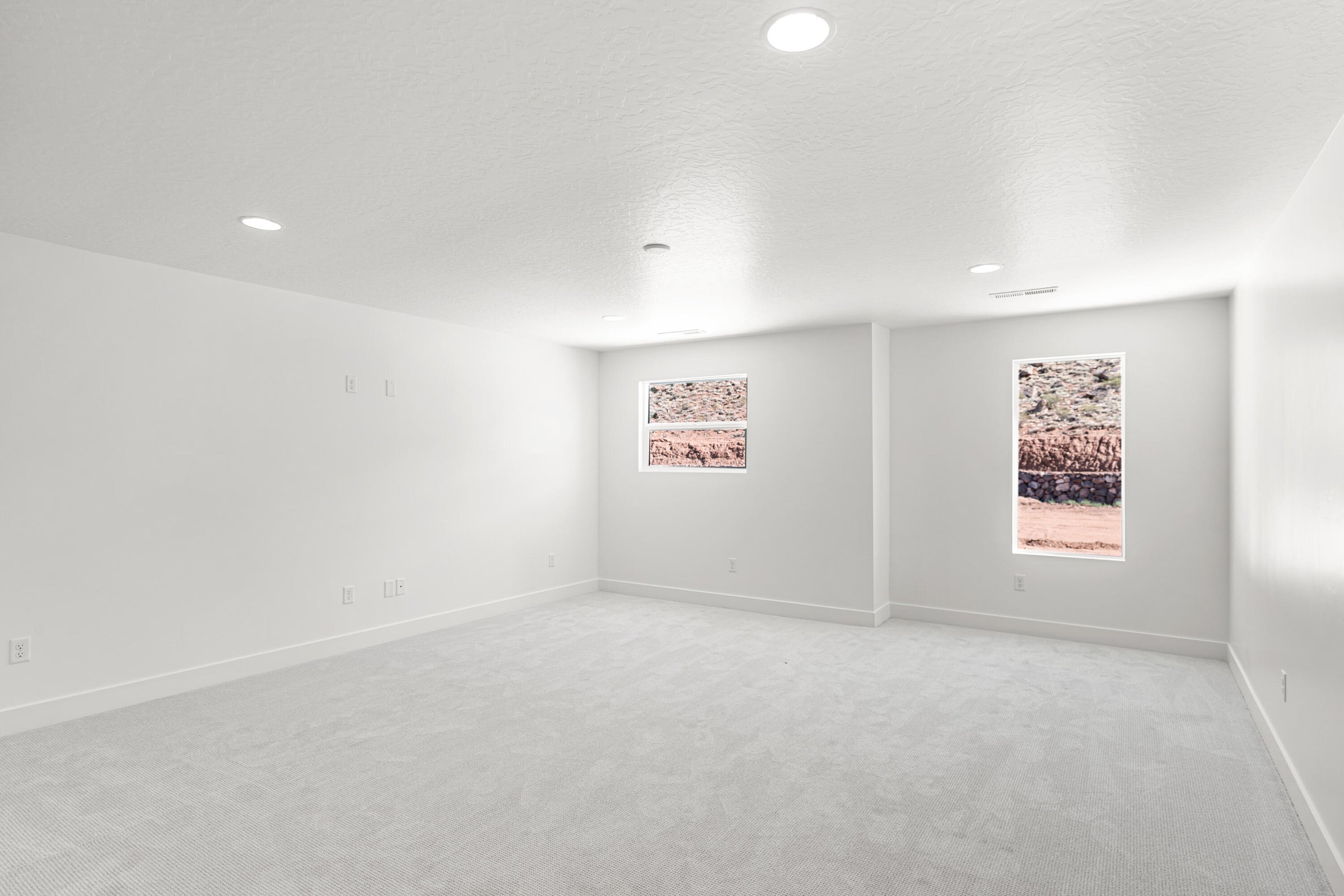 Spacious room featuring light-colored carpeting, white walls, and recessed lighting