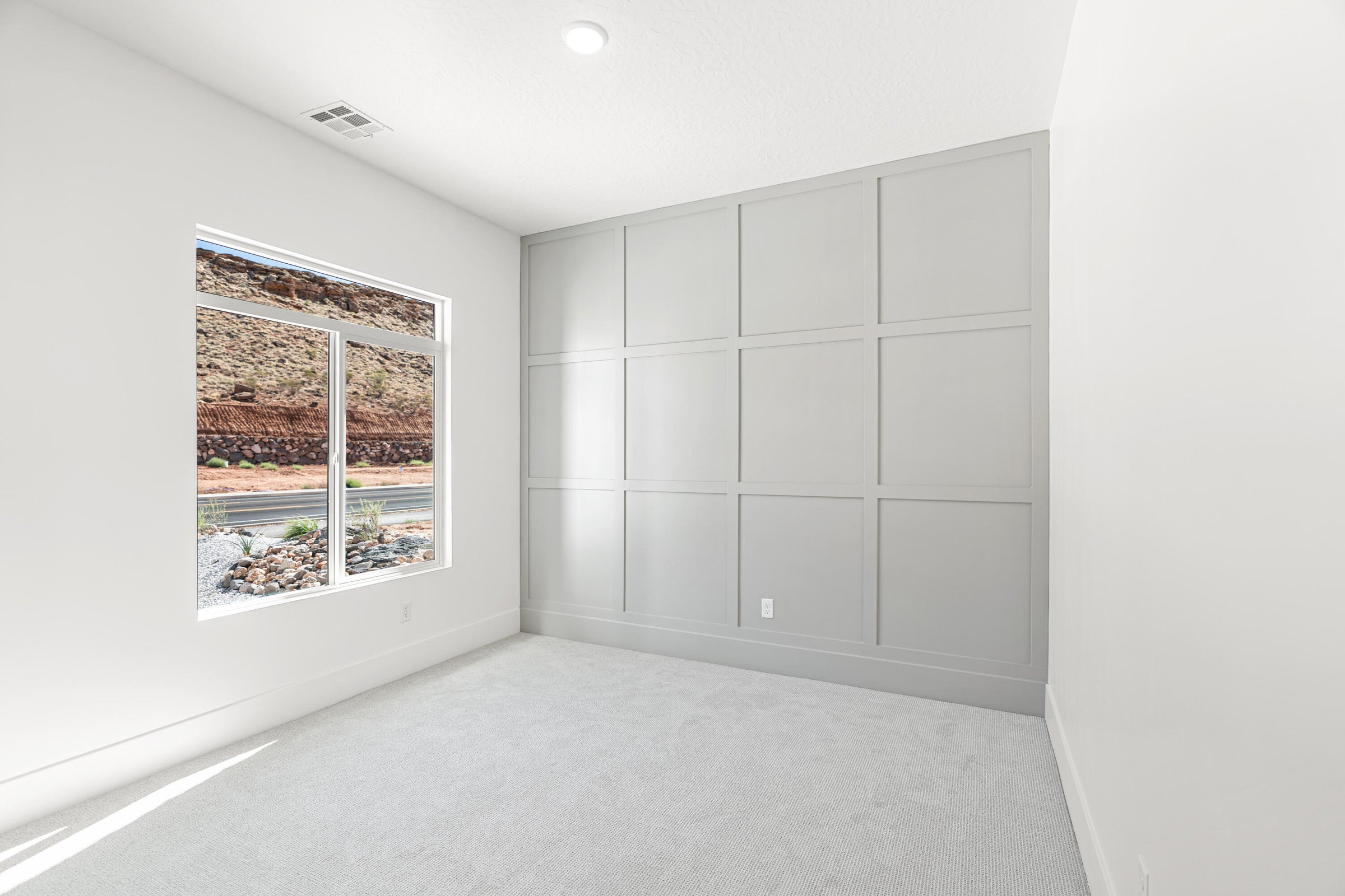 Neutral-toned room featuring a panel accent wall, plush carpet flooring, a large picture window, and recessed ceiling lighting