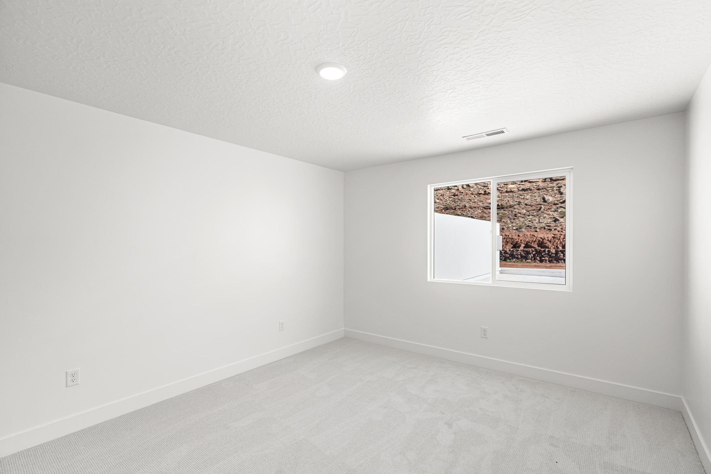 Neutral-toned room featuring a single window, recessed lighting, white walls, and light-colored carpet flooring