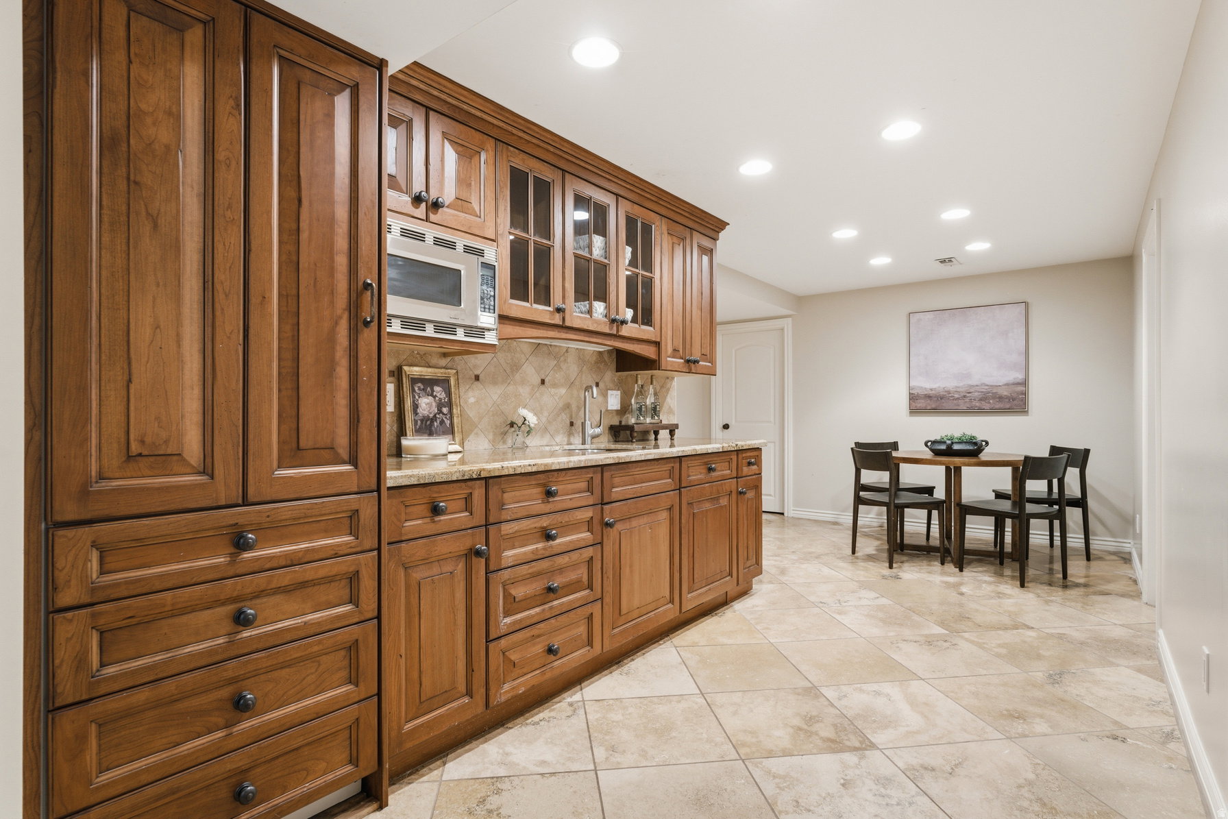 Built-in cabinetry with glass-front uppers and ample storage, stone tile backsplash, and recessed lighting