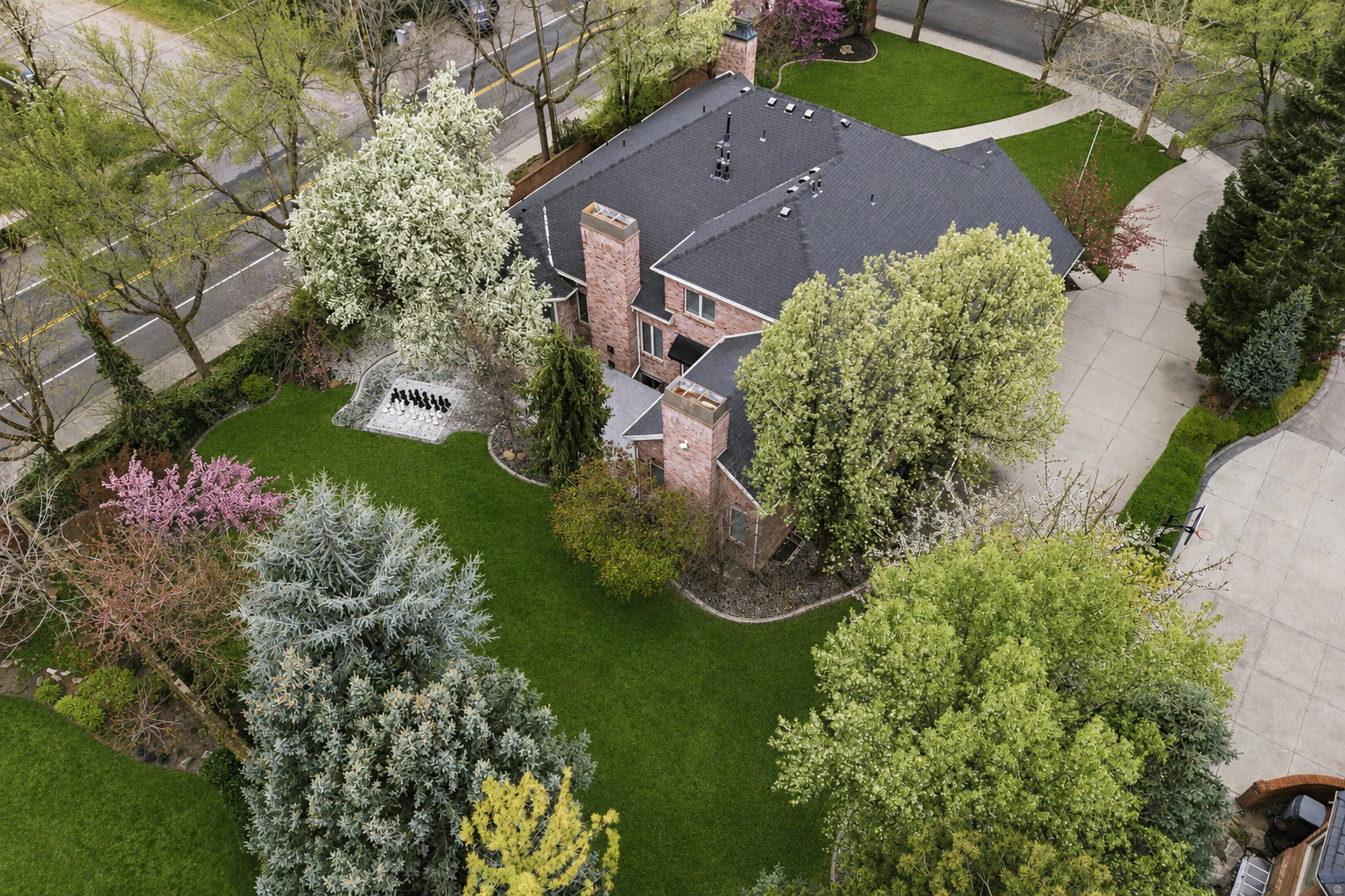 Brick exterior residence with a dark shingle roof and multiple chimneys