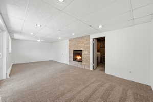 Spacious room featuring a stacked stone fireplace with a black firebox, recessed lighting, and soft carpet flooring