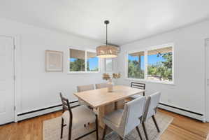 Dining area featuring wood-finish flooring, white walls, and a woven pendant light fixture