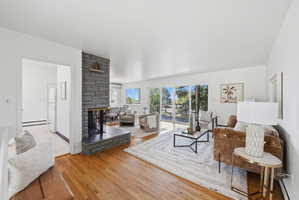 Spacious living area featuring hardwood flooring, a stone-clad fireplace, and double sliding glass doors leading to an outdoor space