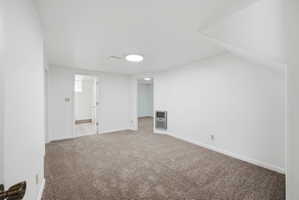 Spacious room featuring neutral carpeting, white walls, and bright overhead lighting