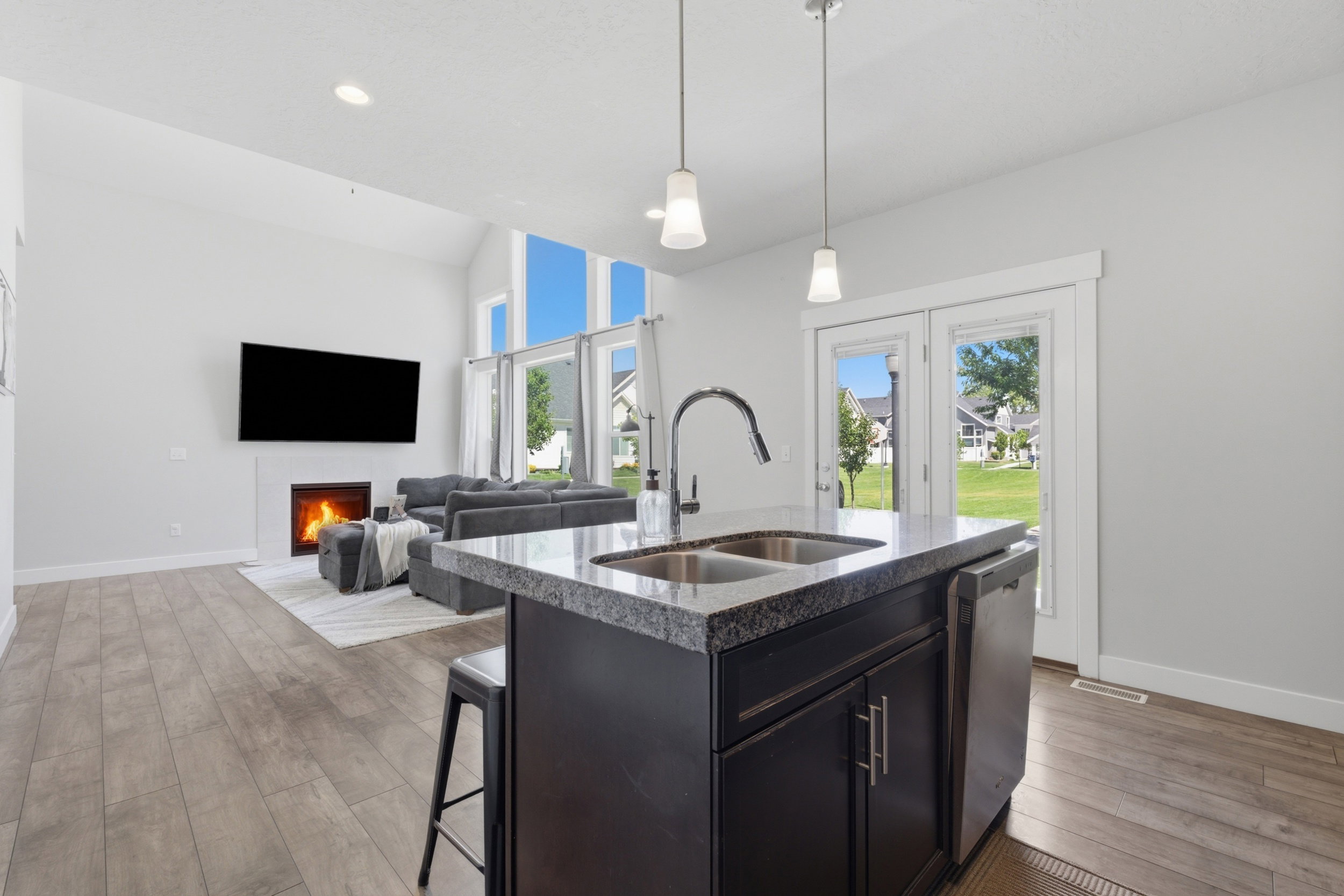 Kitchen island featuring a dual basin sink with a gooseneck faucet, dark cabinetry, and a granite-style countertop