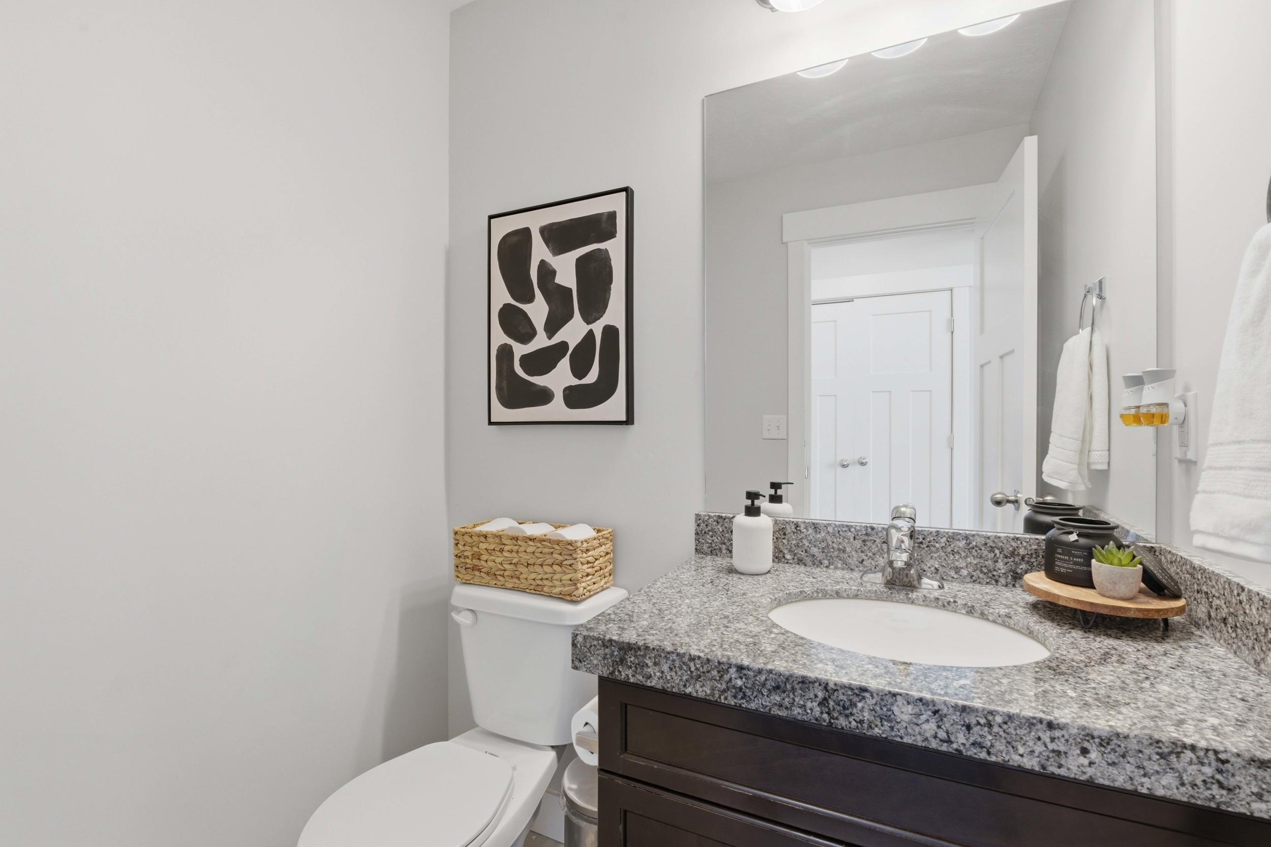 Bathroom vanity featuring a speckled countertop, undermount sink, and dark wood-finish cabinetry