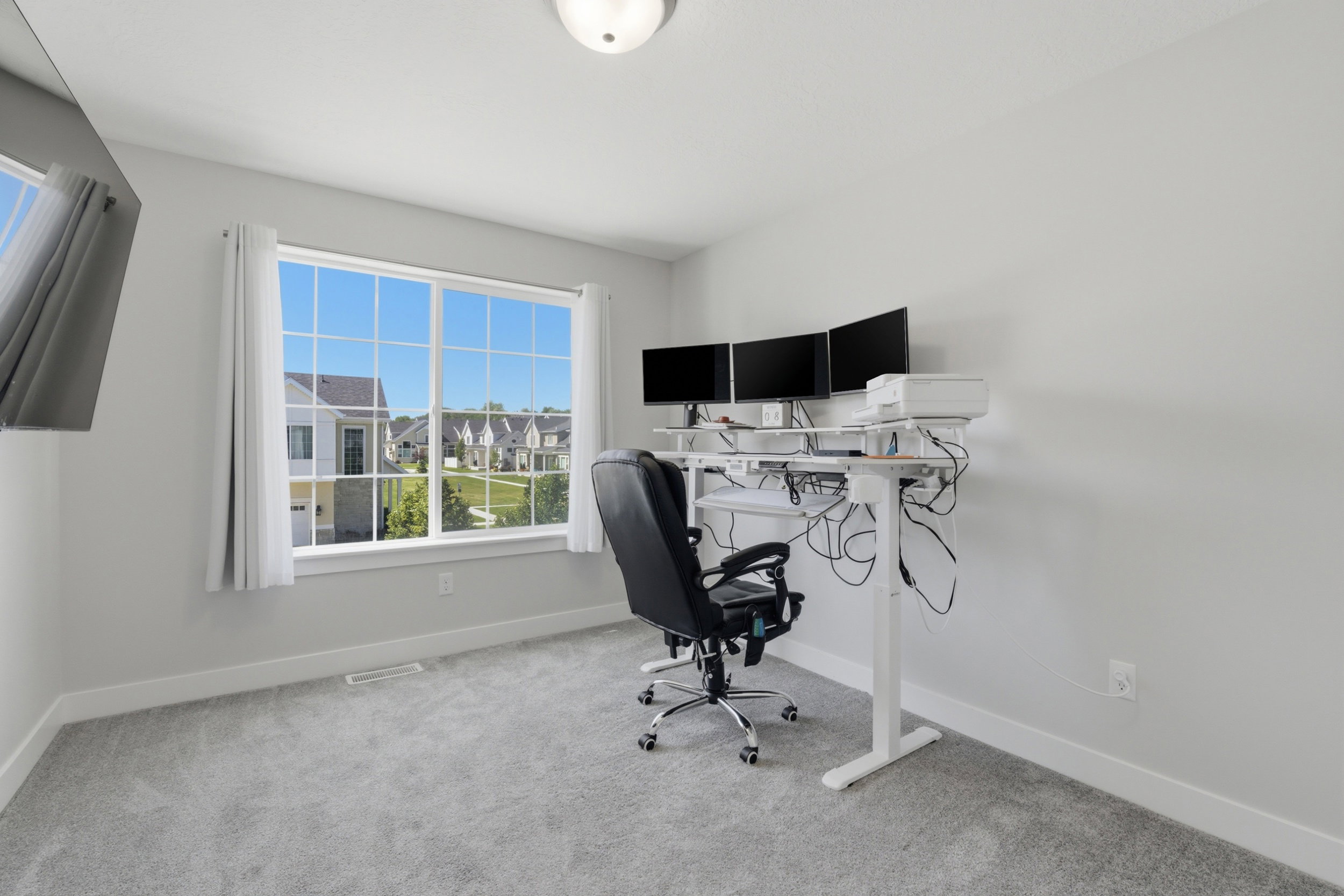 Bright room featuring a large multi-pane window, light gray carpeting, neutral wall paint, and white trim