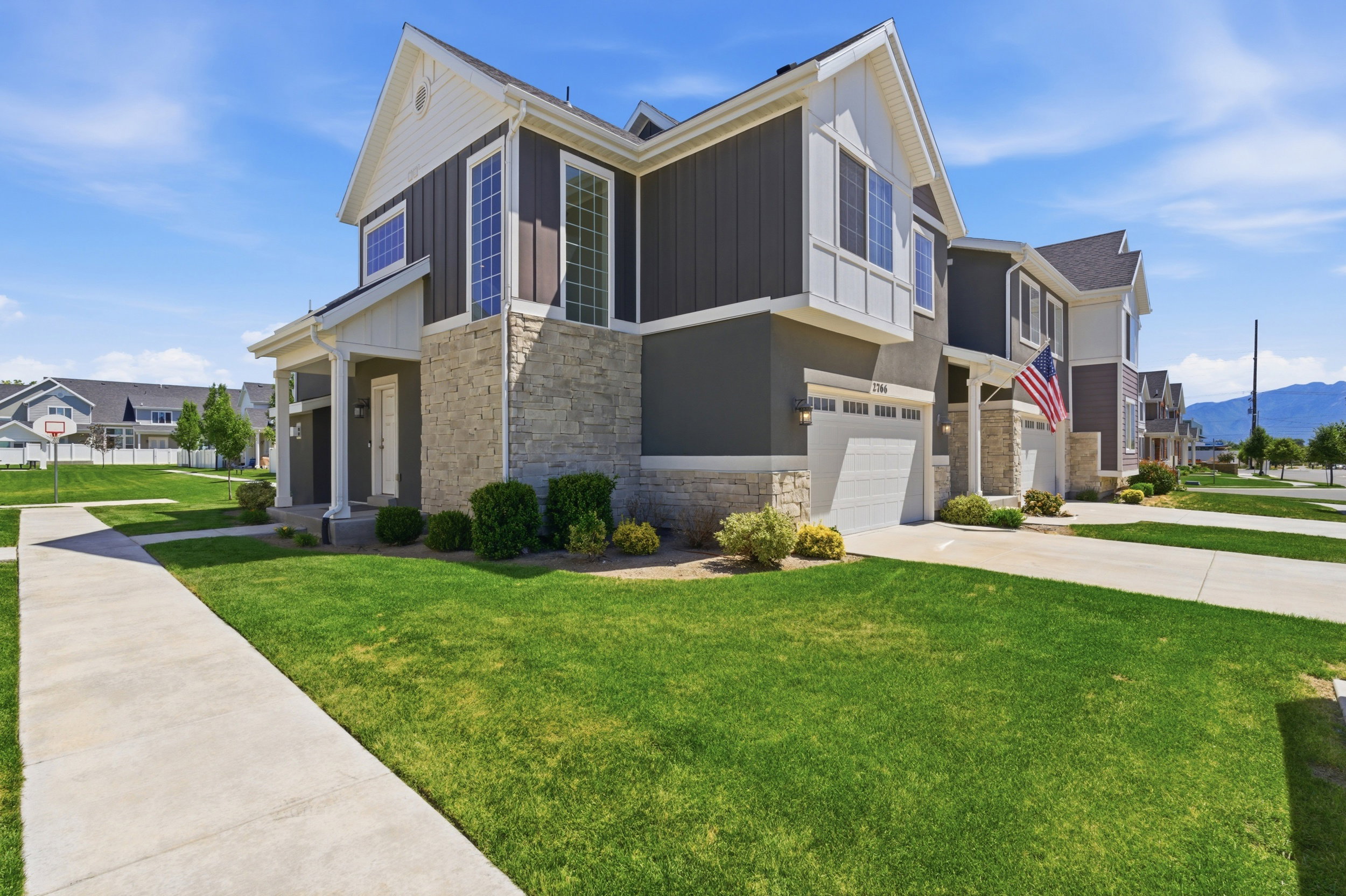 Modern multi-story property featuring dark siding, light stone accents, a white trim, an attached garage, and a covered entryway