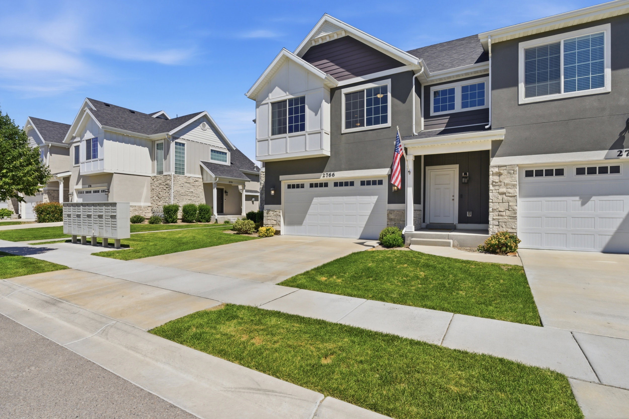 Contemporary multi-story residence featuring a two-car garage, stone facade accents, and a covered entryway