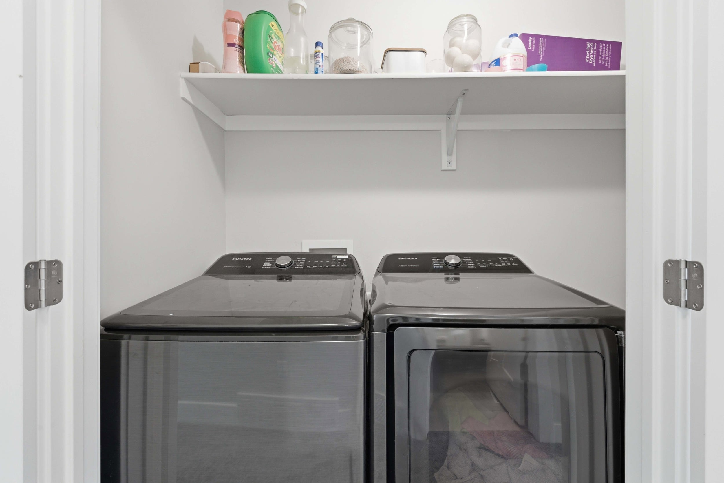 Dedicated laundry area featuring a washer and dryer set, accompanied by an overhead storage shelf
