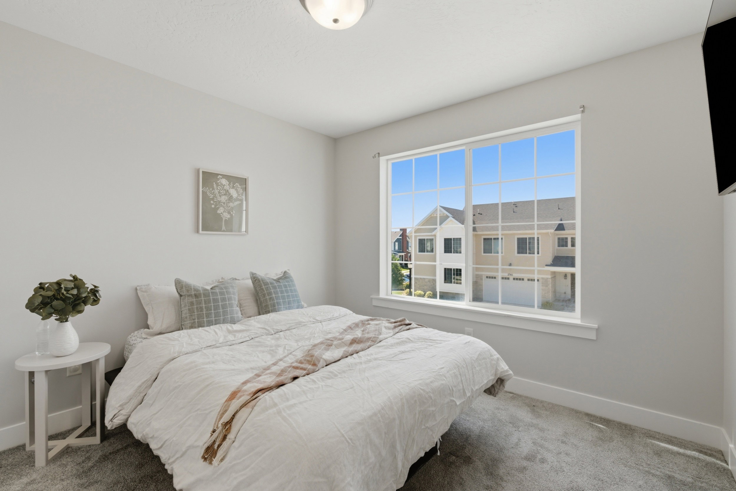 Room featuring light-toned walls, gray carpet flooring, and a large window with white muntins