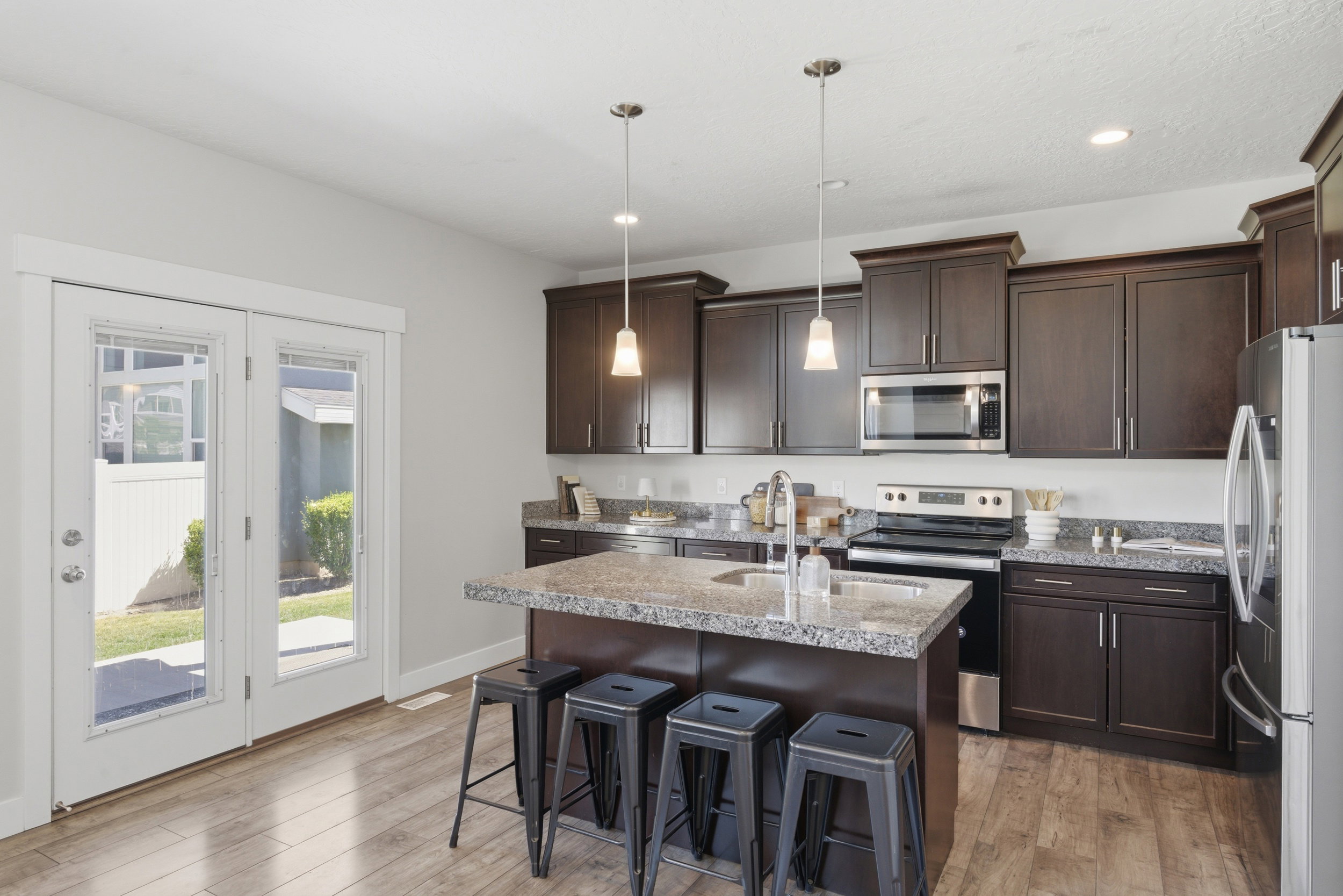 Kitchen featuring dark wood cabinetry, stainless steel appliances, and a central island with a stone-finish countertop