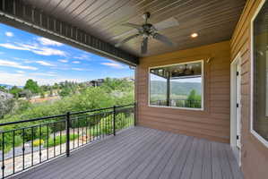 Expansive outdoor deck featuring wood-finish flooring, black metal railing, and a ceiling fan