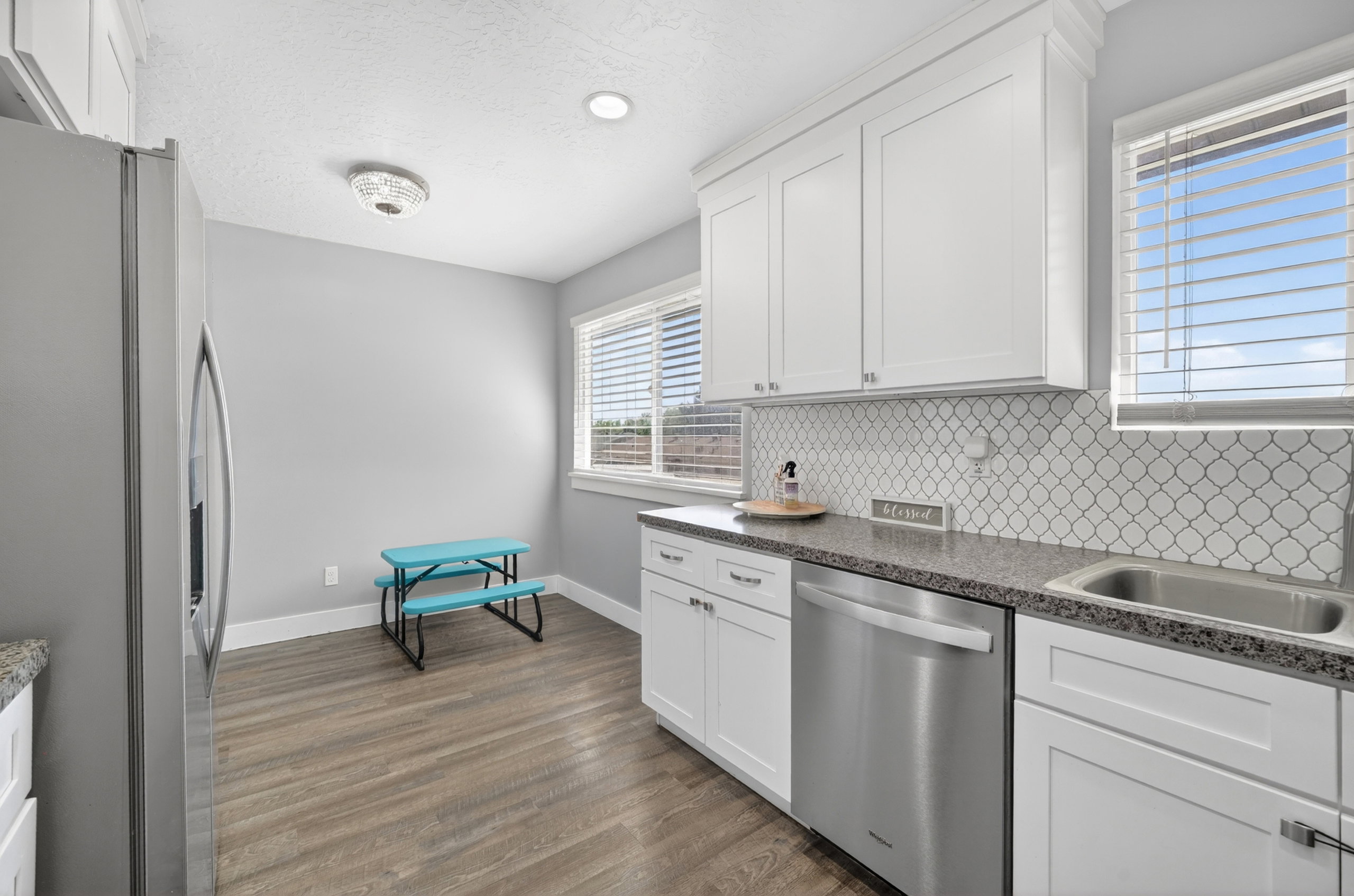 Kitchen featuring white cabinetry, stone-finish countertops, stainless steel appliances, and wood-finish flooring