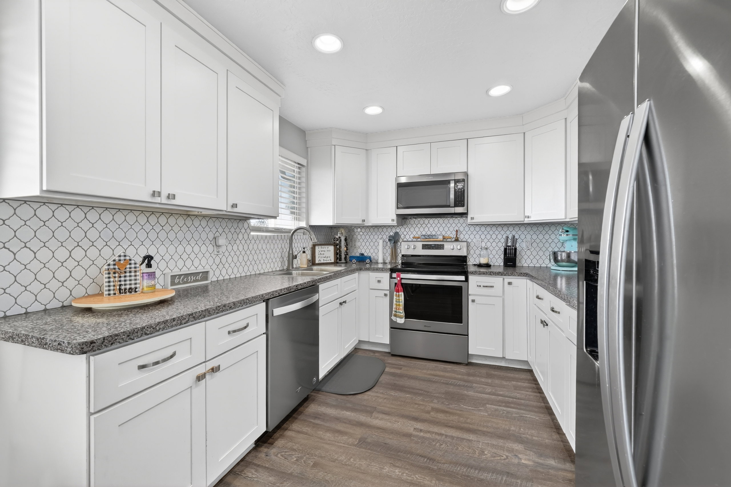 Contemporary kitchen featuring white cabinetry, granite countertops, and a full tile backsplash