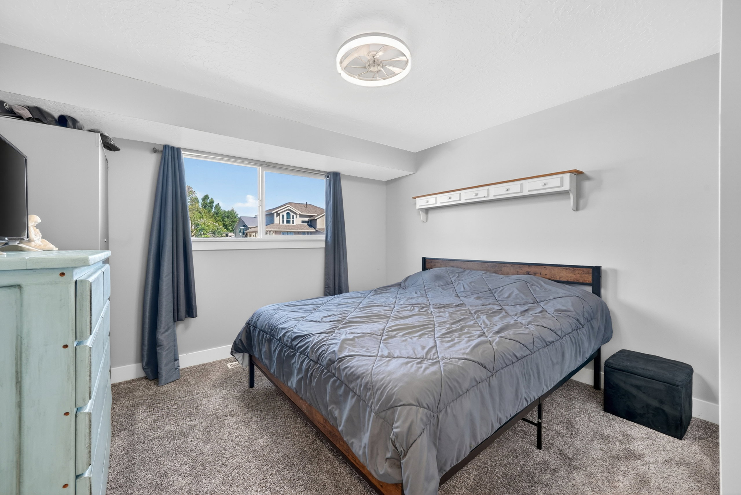Carpeted bedroom with a window, white baseboards, and a ceiling fan