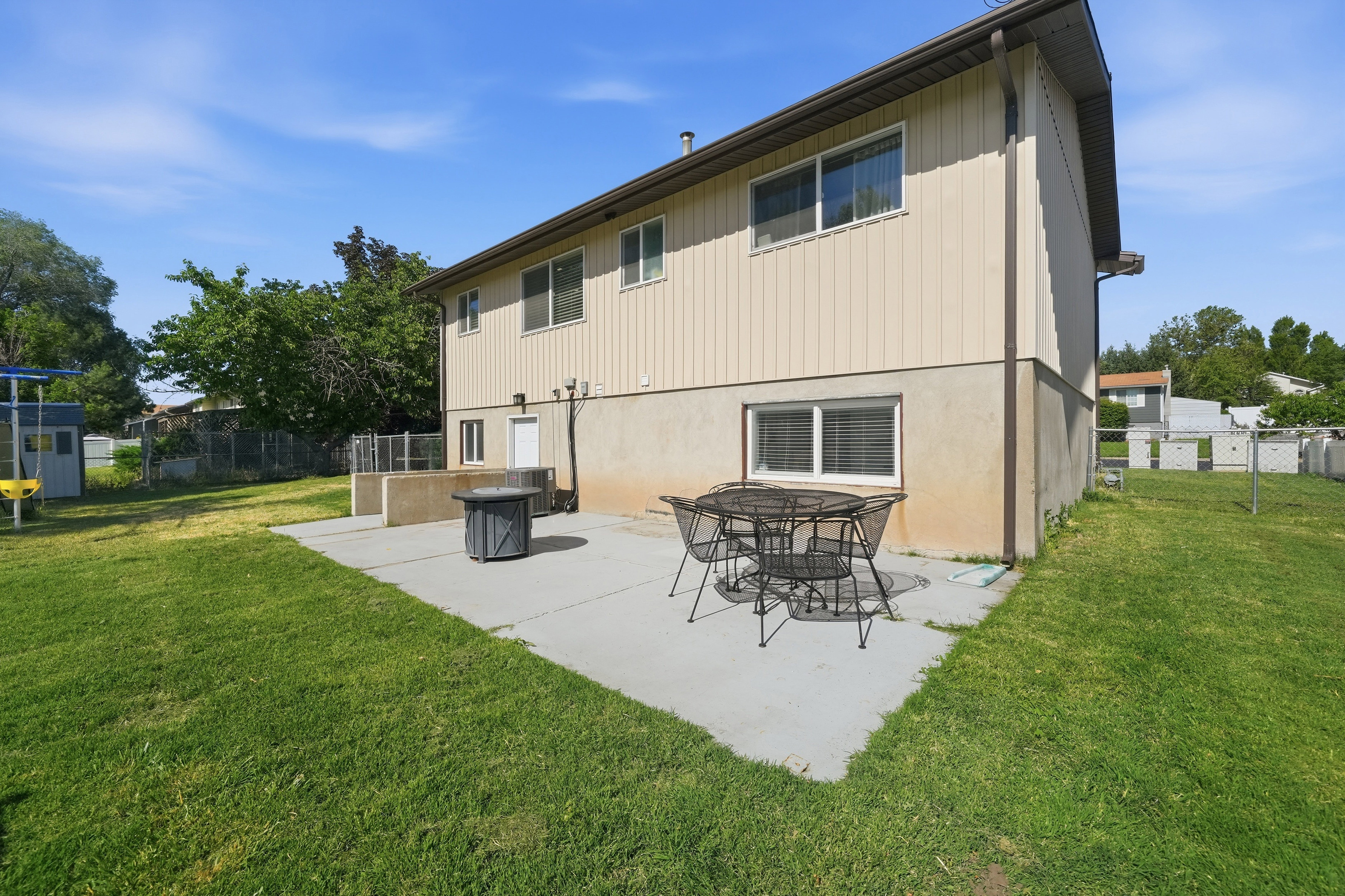 Expansive rear yard featuring a concrete patio, exterior access, and a manicured lawn