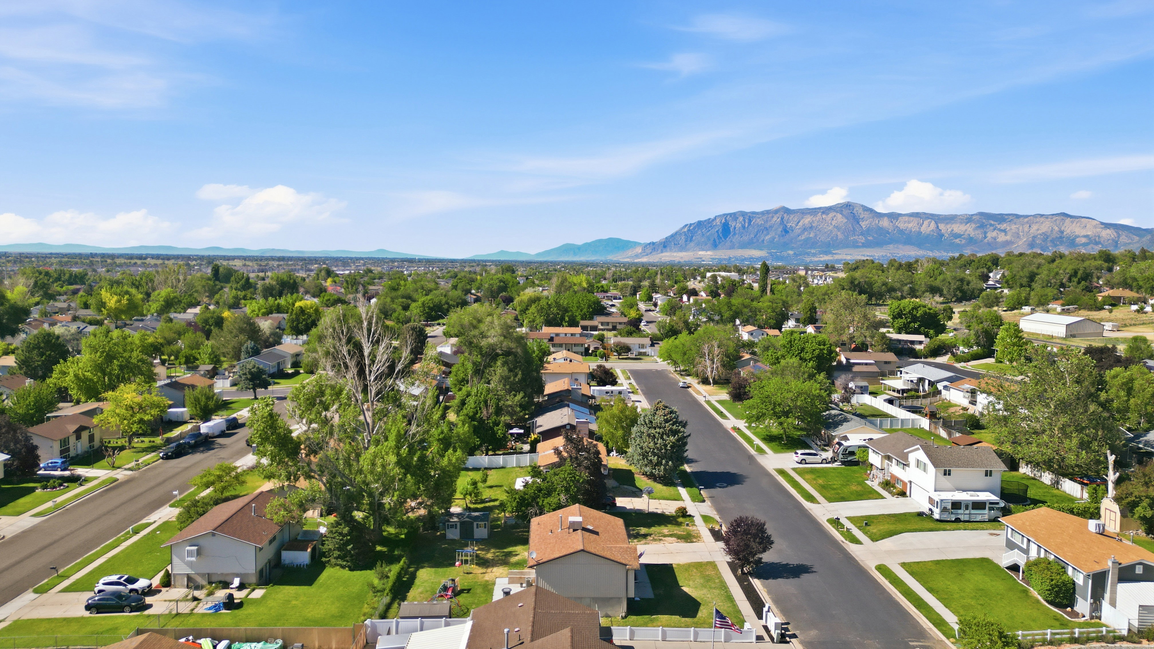 Residential neighborhood with mature trees, paved streets, and mountain backdrop