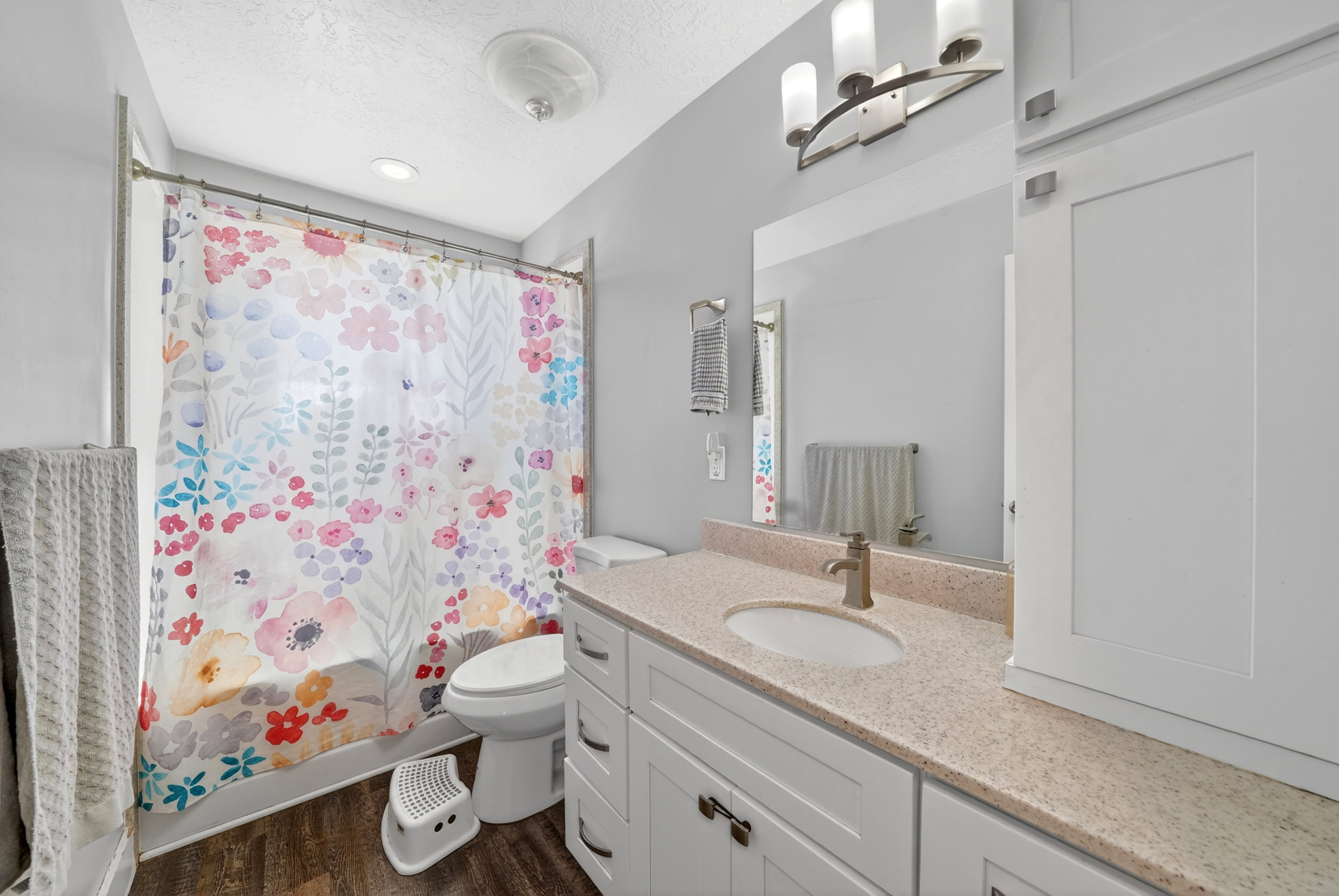 Bathroom featuring a spacious vanity with an integrated sink, light-toned countertop, and white cabinetry