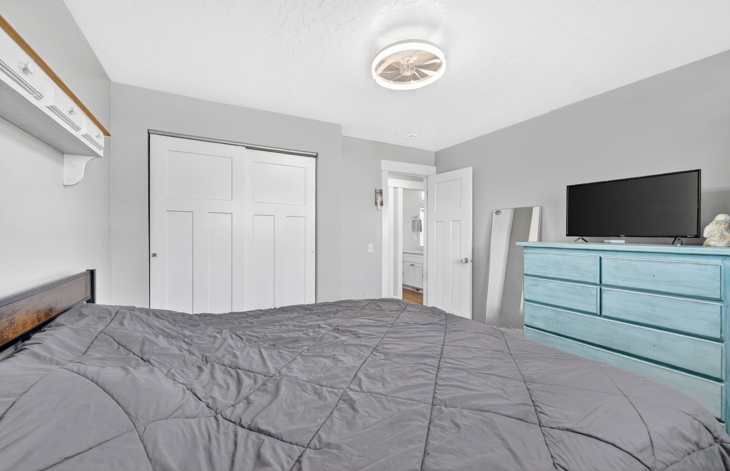 Recessed lighting and a ceiling fan illuminate this space, featuring light gray walls, white trim, and a white six-panel sliding closet door