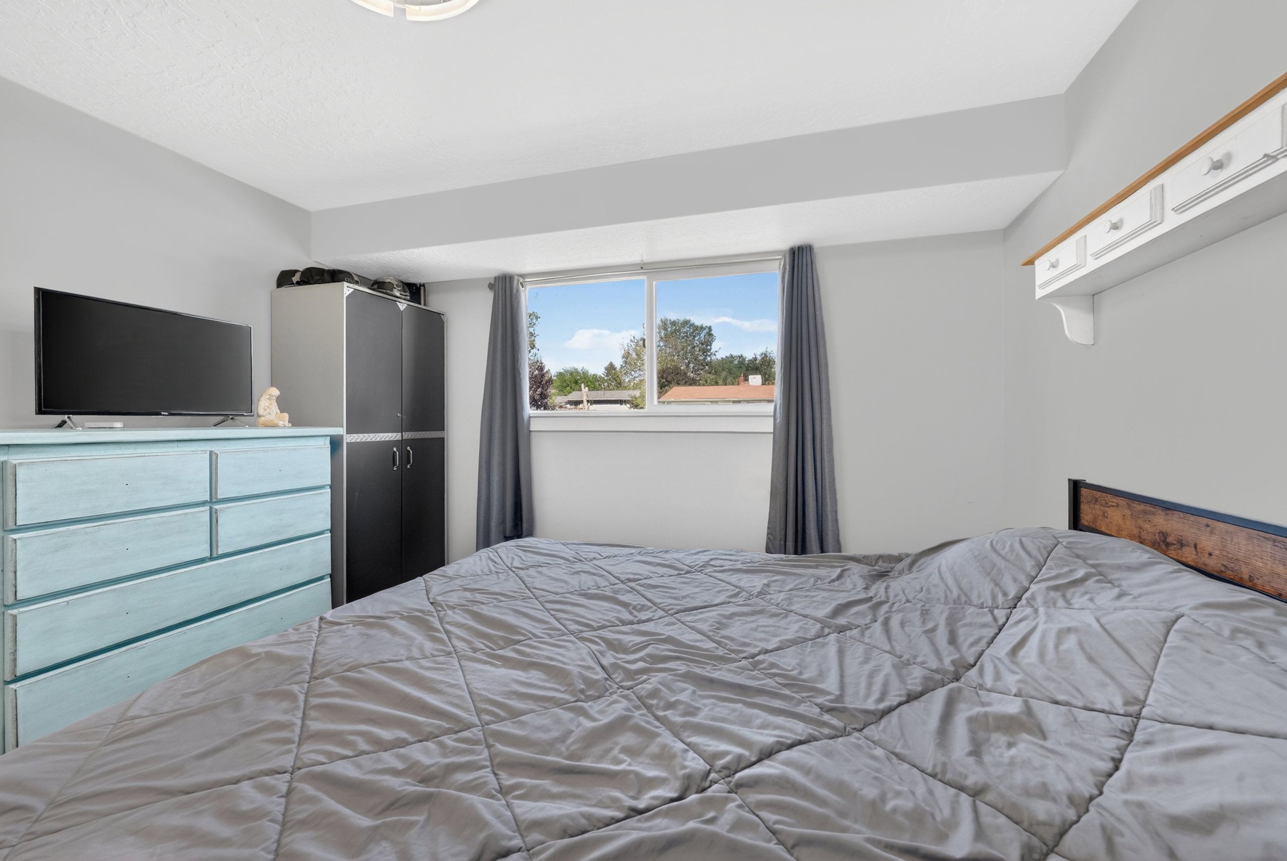 Bedroom featuring a window with natural light, light gray painted walls, and a ceiling-mounted light fixture