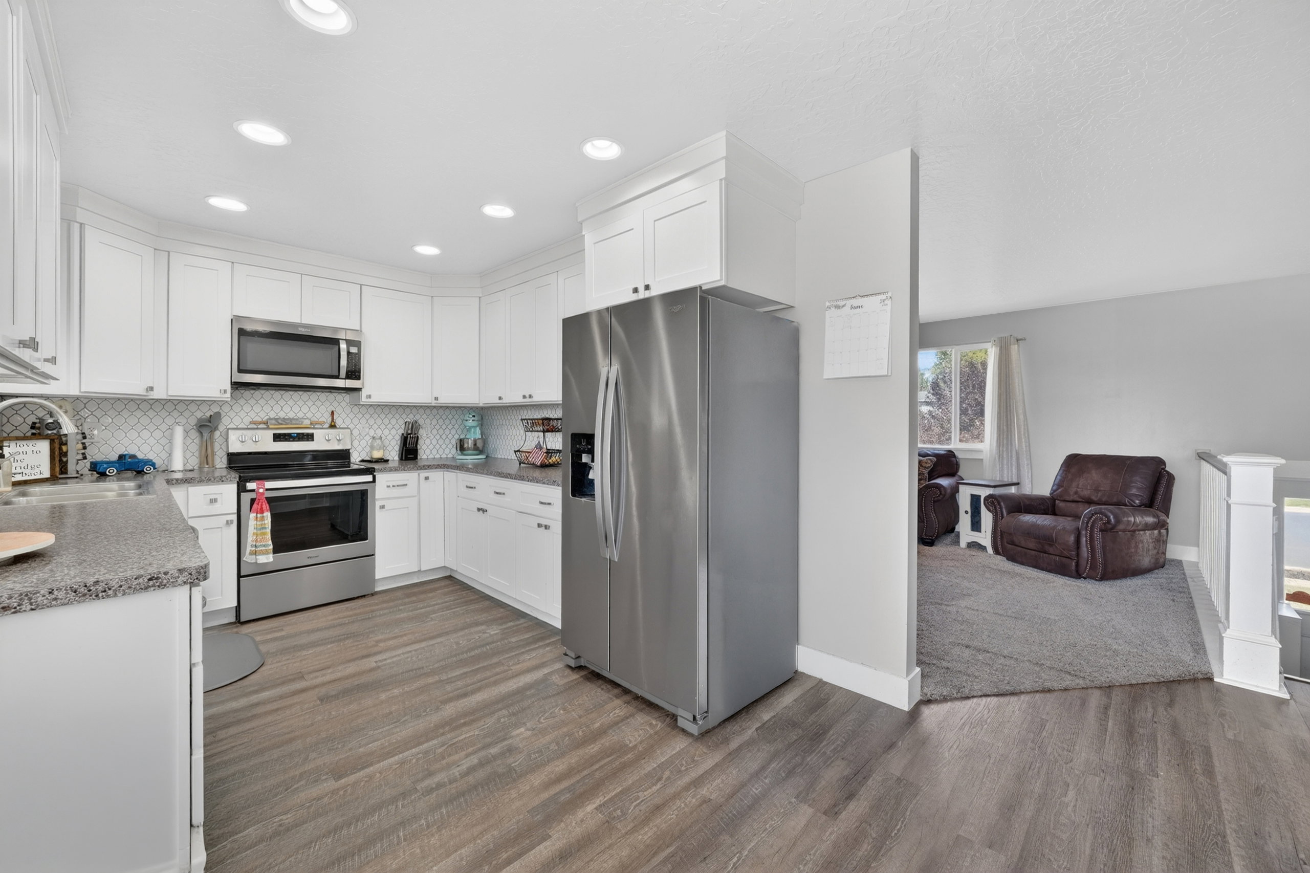 Contemporary kitchen featuring white cabinetry, stainless steel appliances, speckled countertops, and a white subway tile backsplash