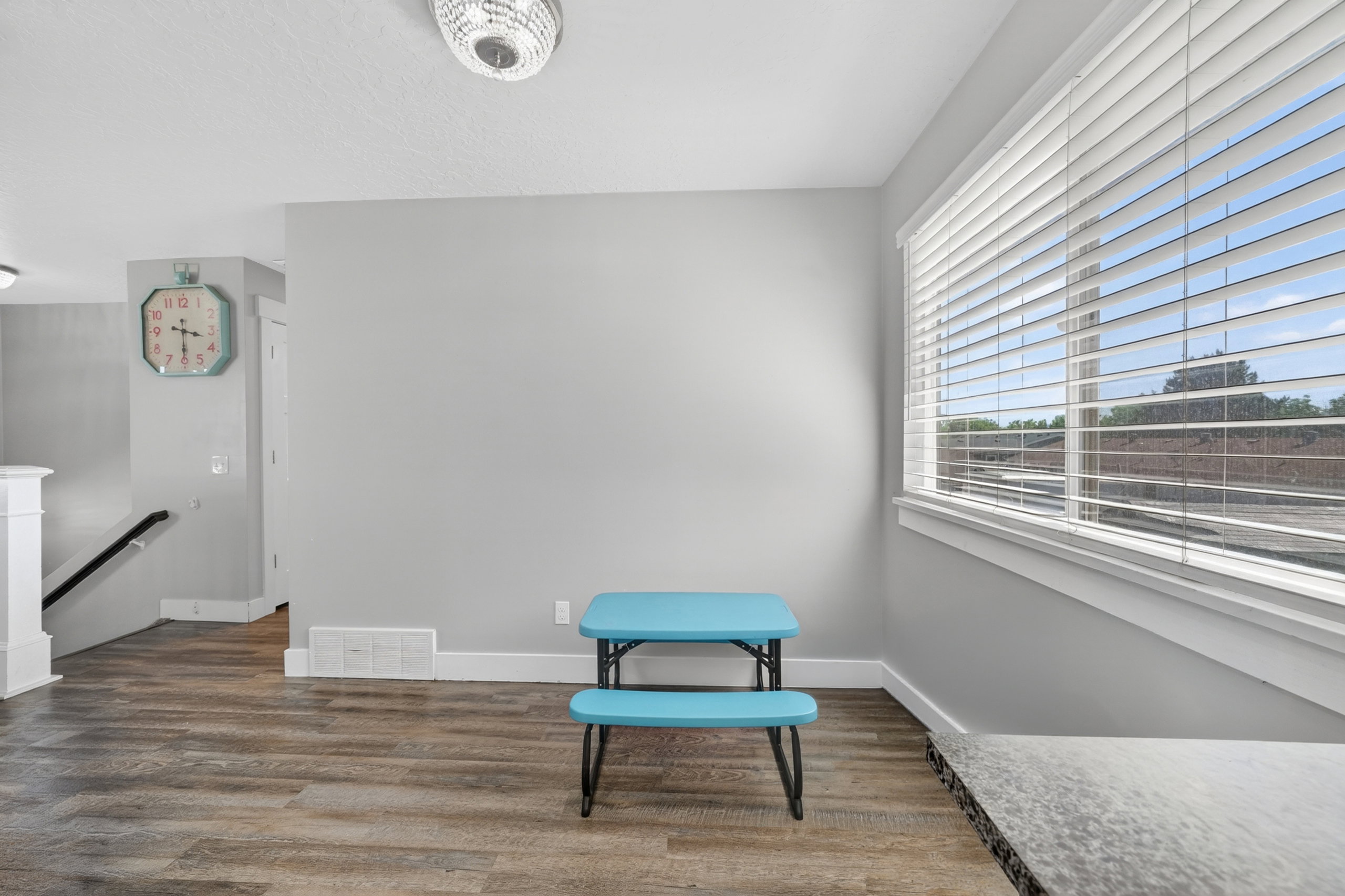Spacious interior with wood-finish flooring, light grey wall paint, and white baseboards