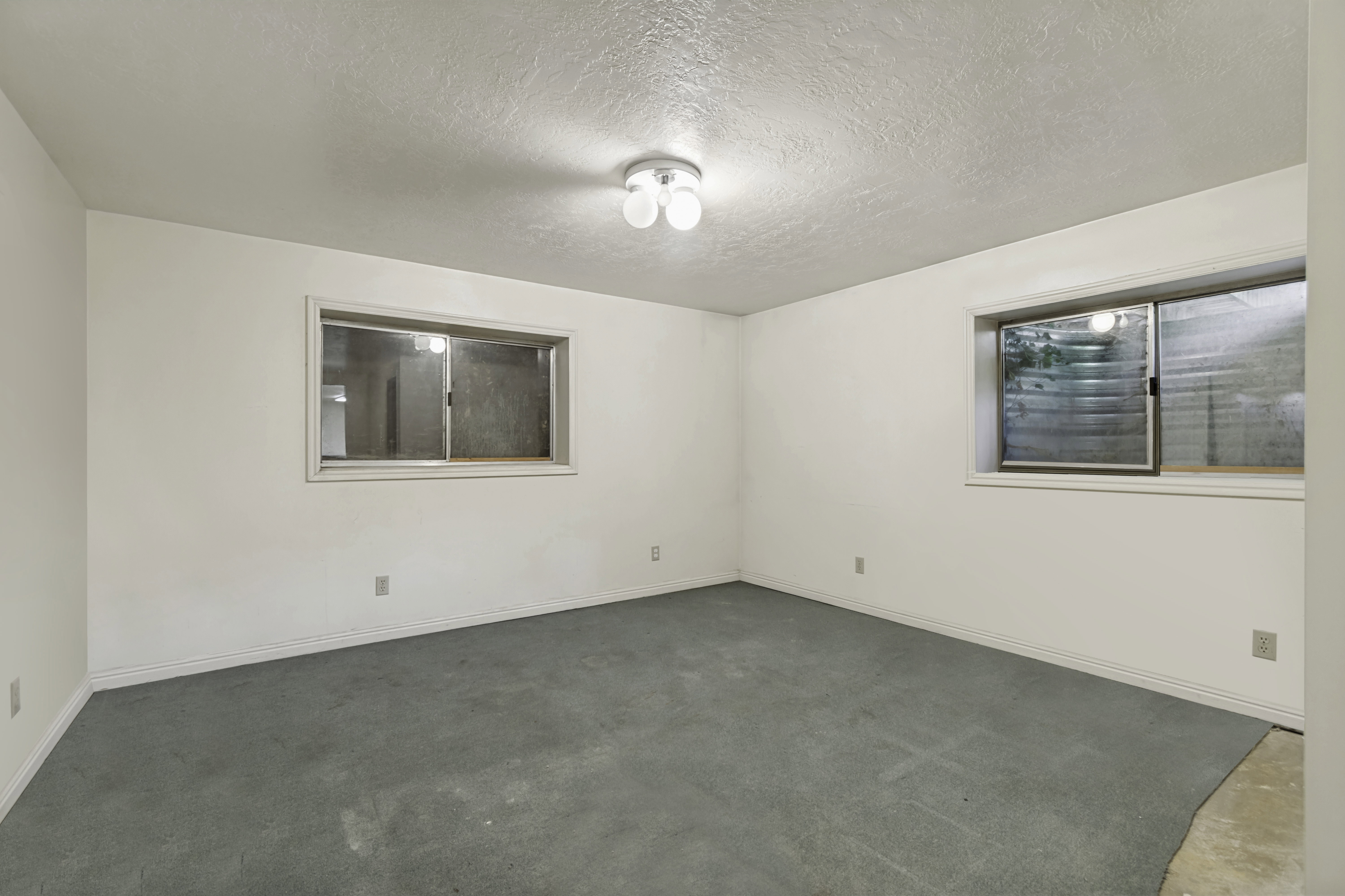Spacious room featuring light-toned walls, a textured ceiling, and flush-mount ceiling lighting