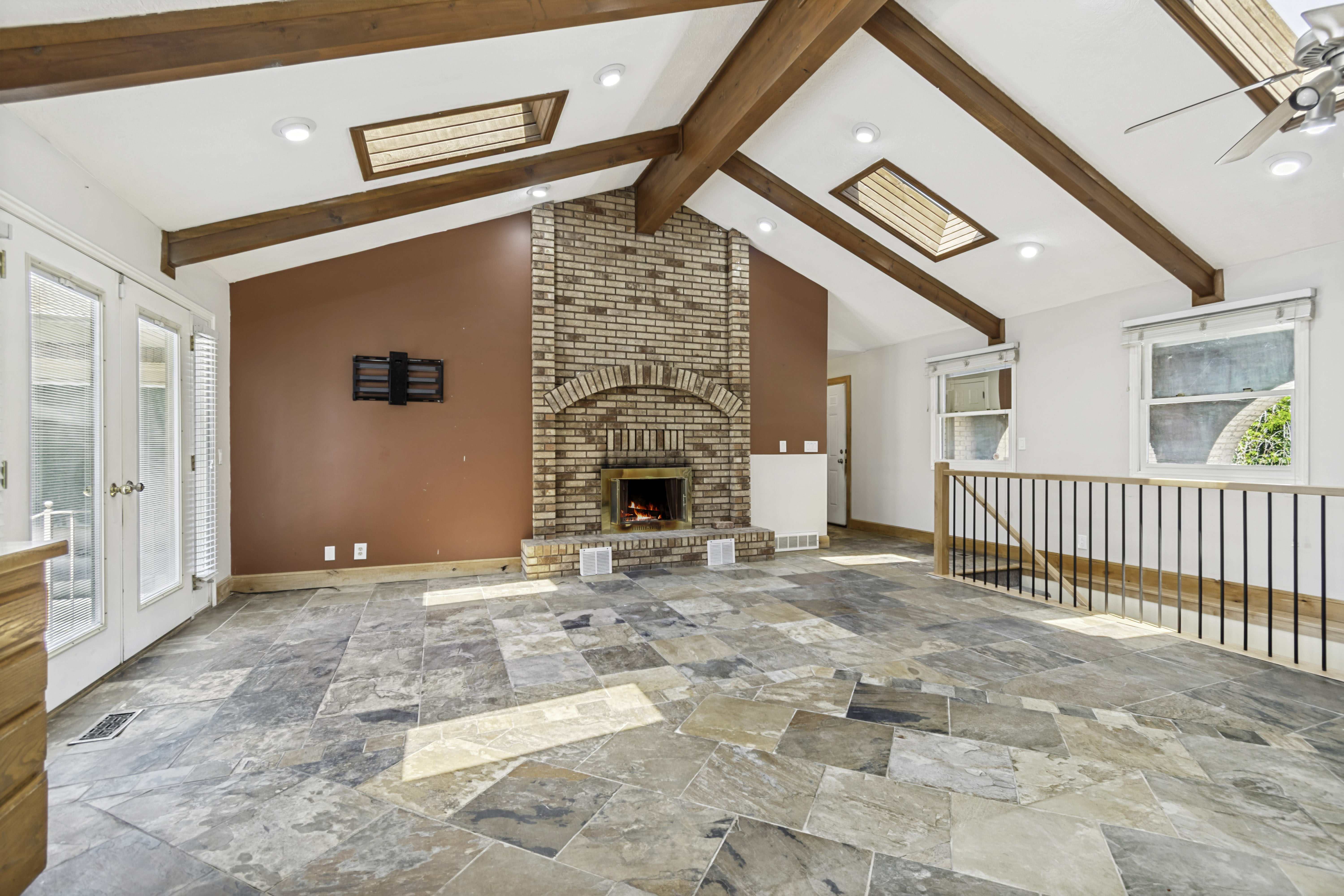 Spacious room featuring vaulted ceilings with exposed wood beams, skylights, and recessed lighting