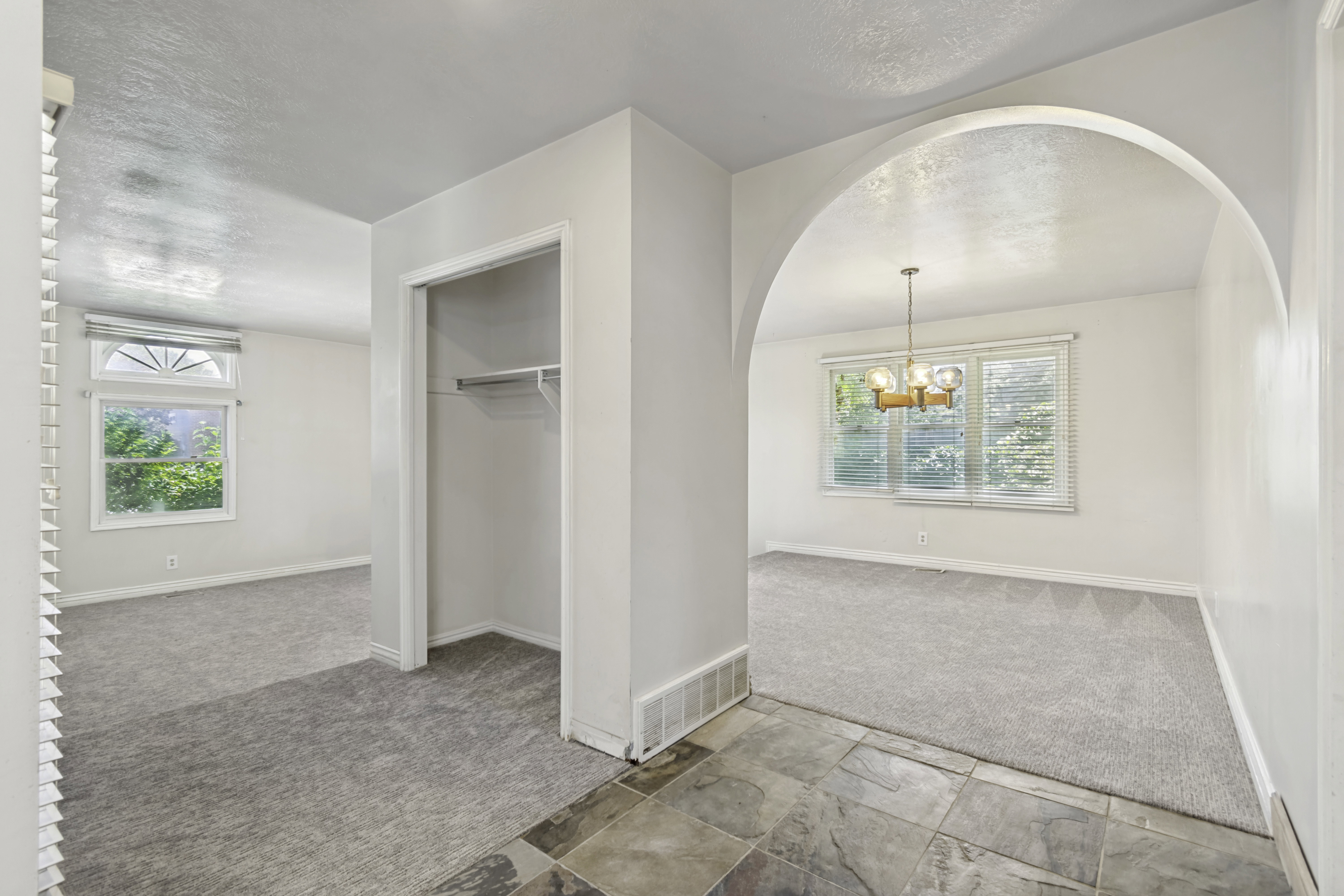 Tiled entryway featuring an arched doorway, leading to a carpeted room with multiple windows, including a decorative fanlight window