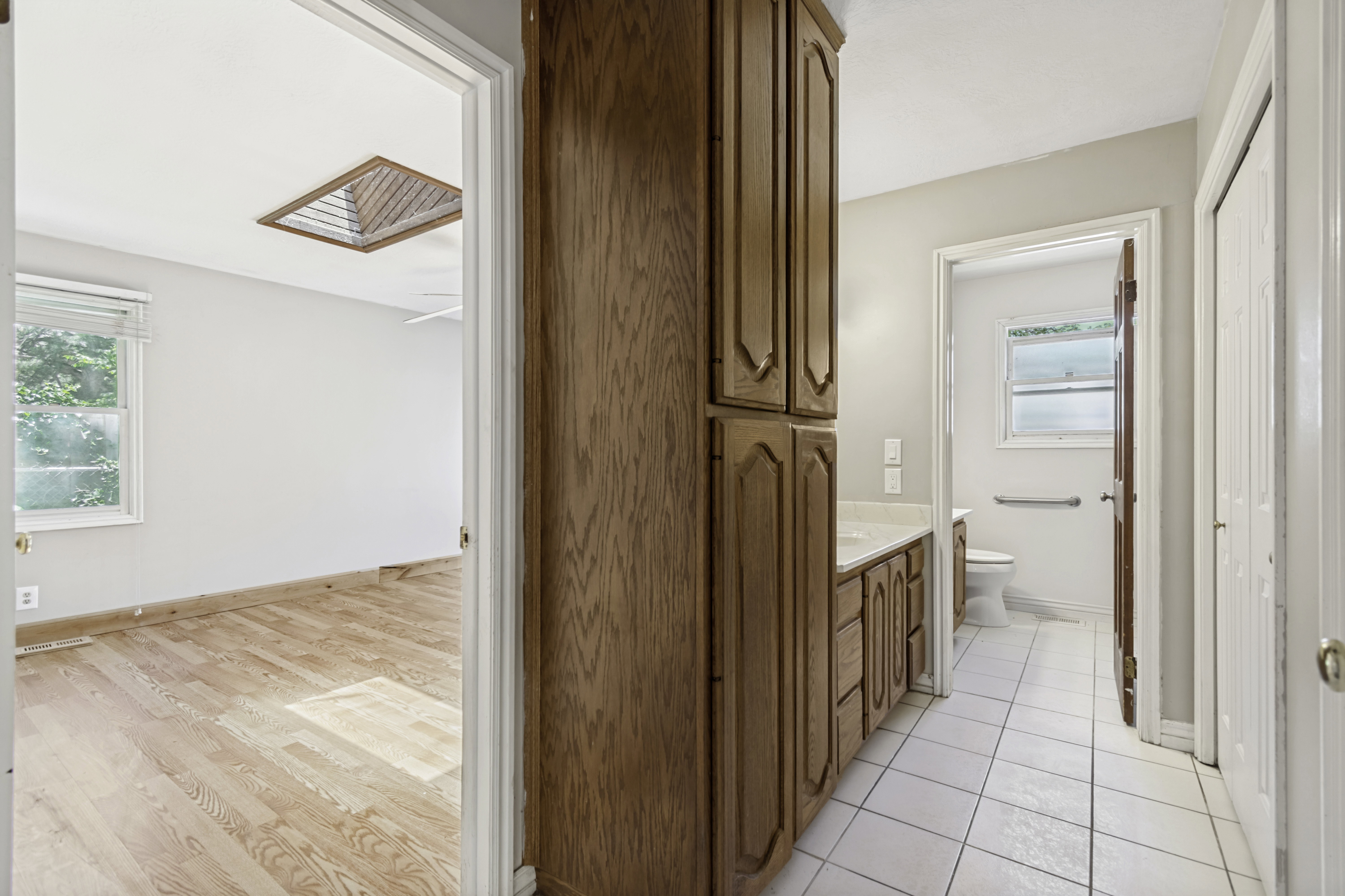 Hardwood flooring in a bedroom featuring a skylight and window