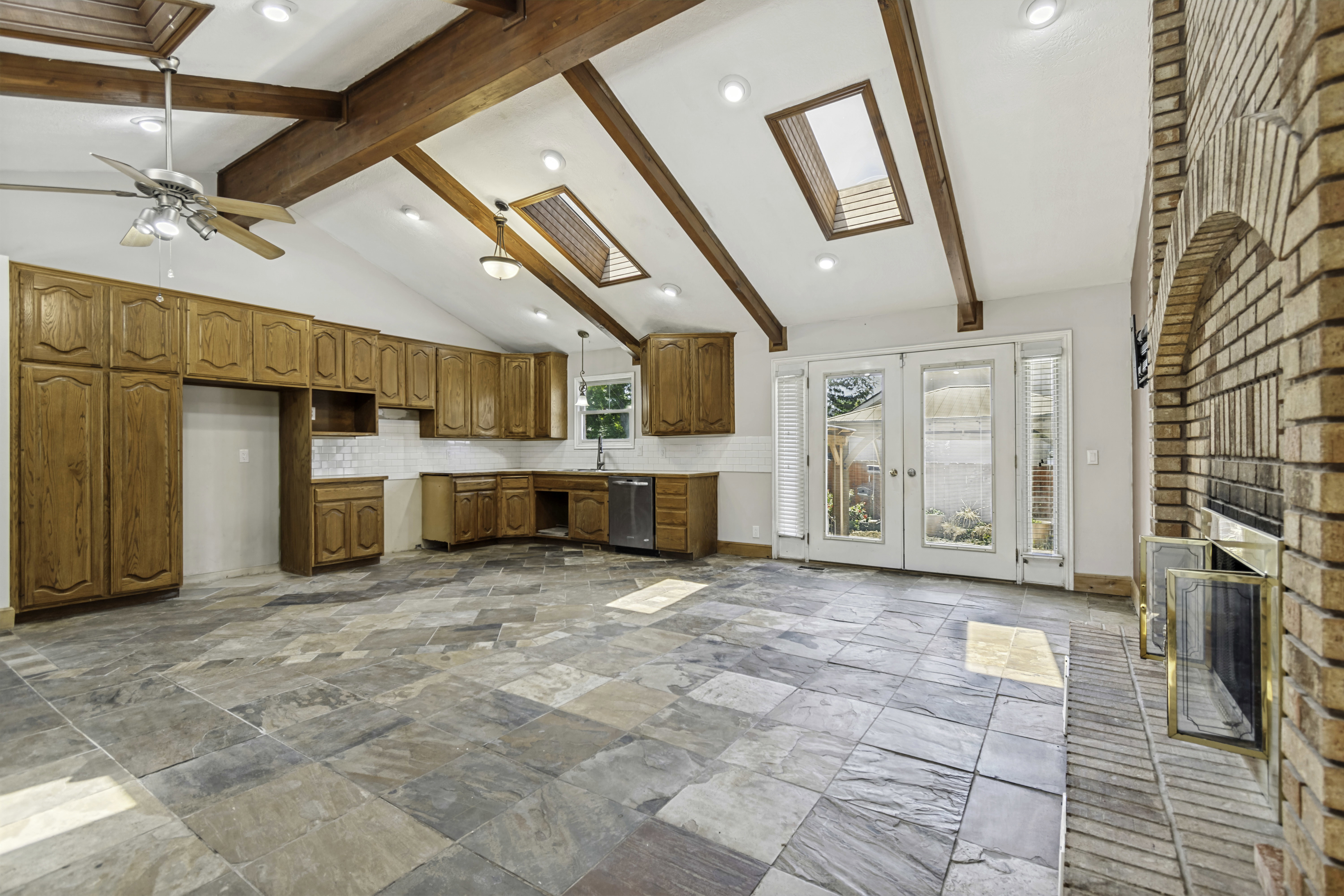 Expansive living area featuring vaulted ceilings with exposed wood beams, skylights, and recessed lighting