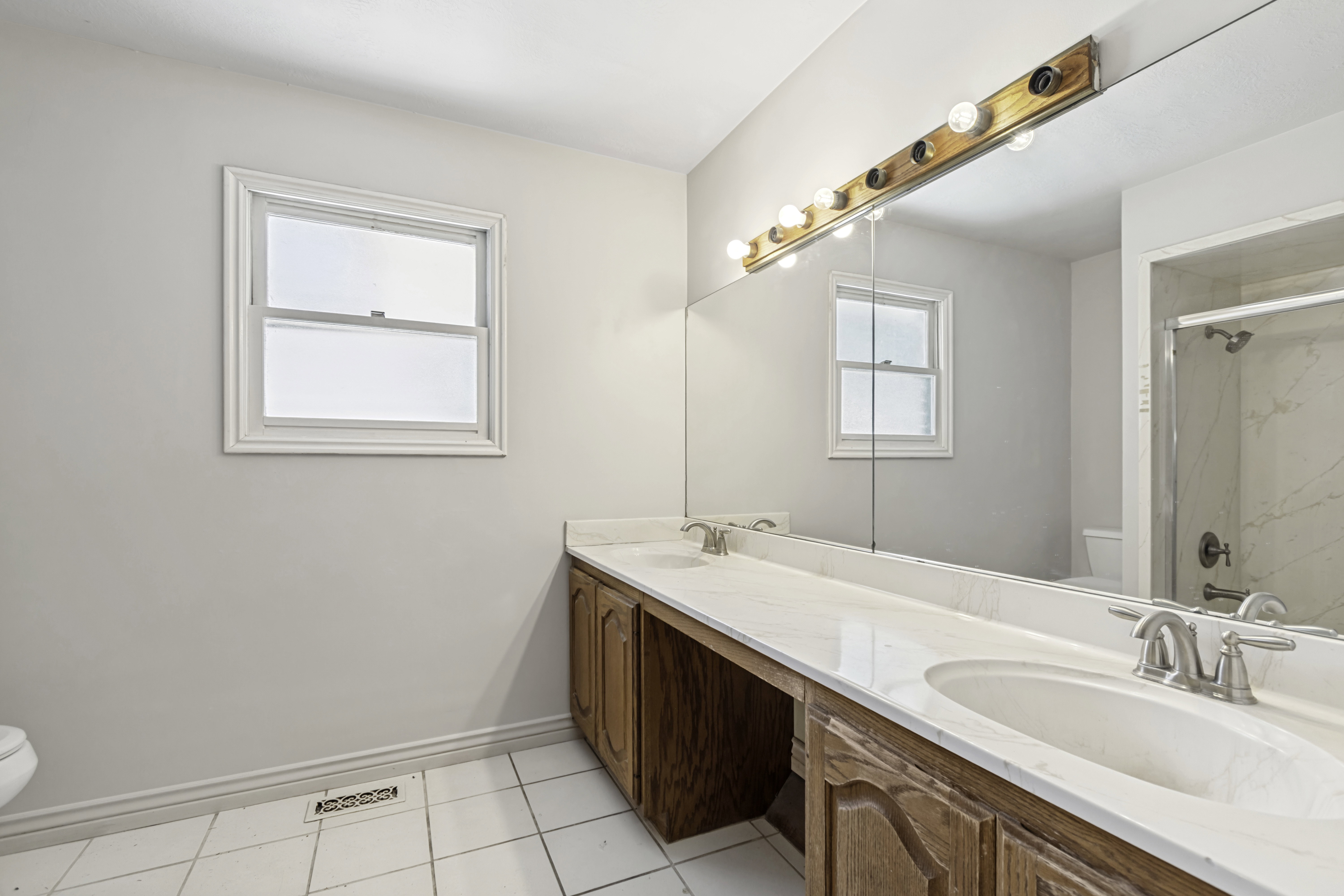 Bathroom featuring a dual vanity with wood cabinetry and light-toned countertops